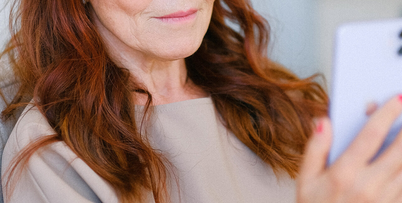 Headshot of a lady's lower part of her face. She has auburn hair and is smiling.