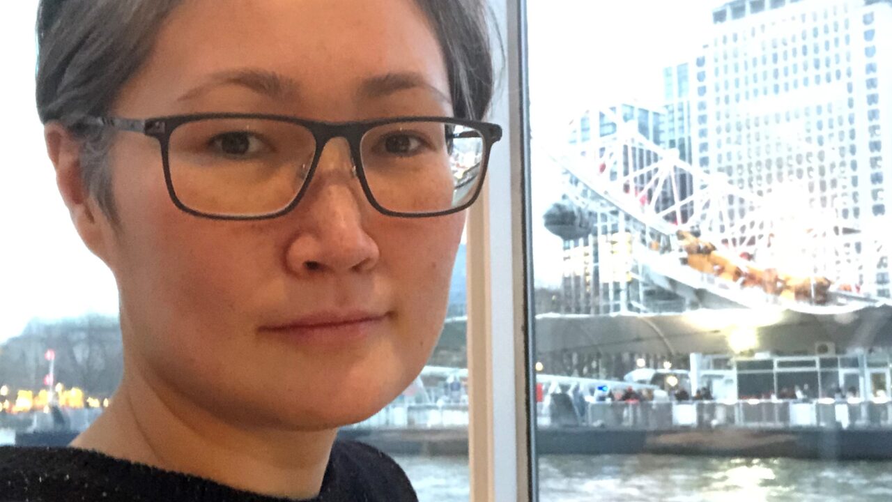 Sightline Volunteer wearing glasses sat on a boat with water in the background