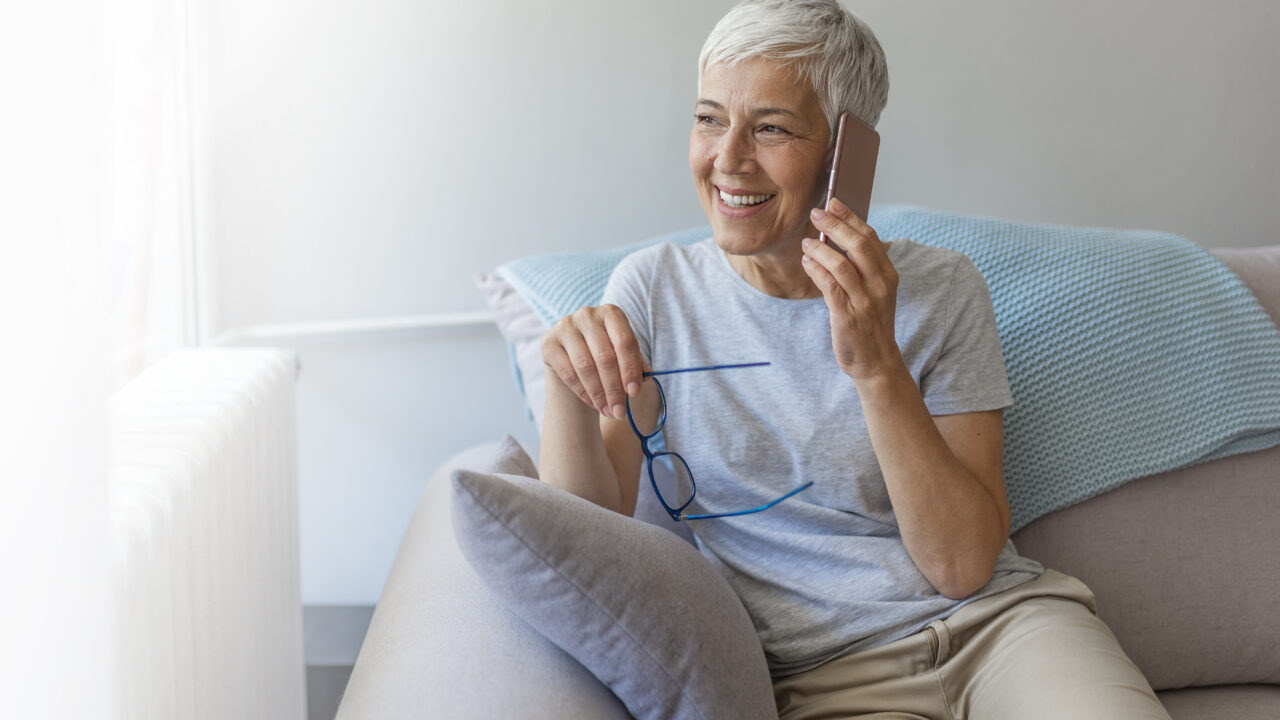 Lady talking on her mobile phone with glasses in the other hand