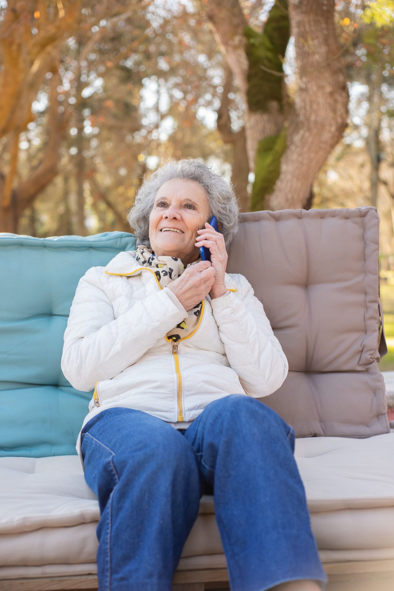 Lady in her eighties sat outside, smiling whilst on a phone call